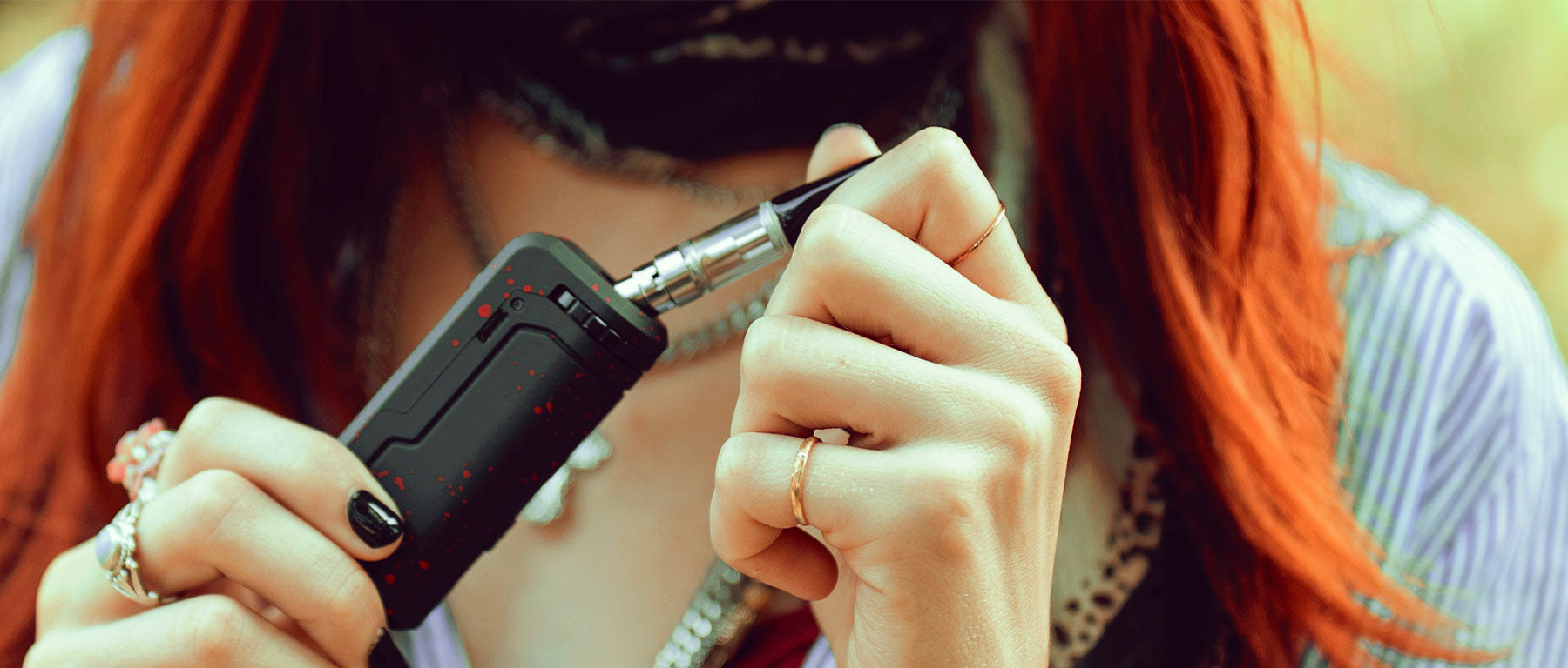 Woman with red hair and blue shirt pulling oil cartridge out of Wulf Mods UNI at park