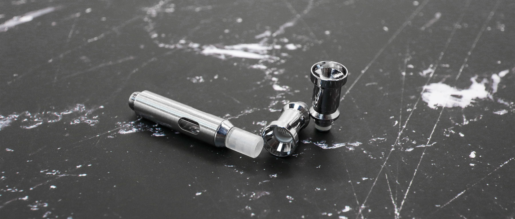 Wulf Mods Atomizers and Tanks laying down on black and white marble textured table