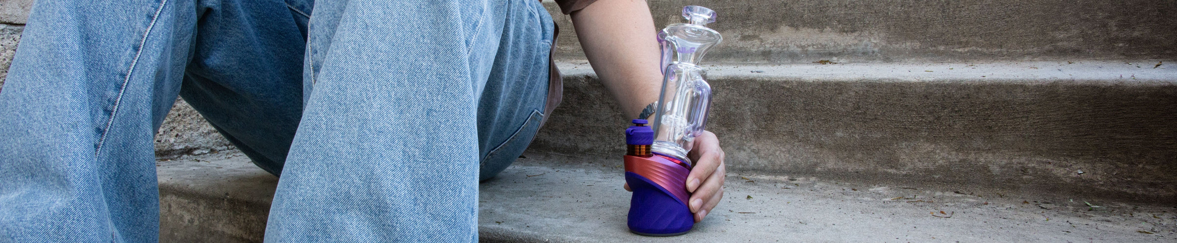 man using the Puffco Peak with Wulf Link Glass Attachment at park with water fountain in background