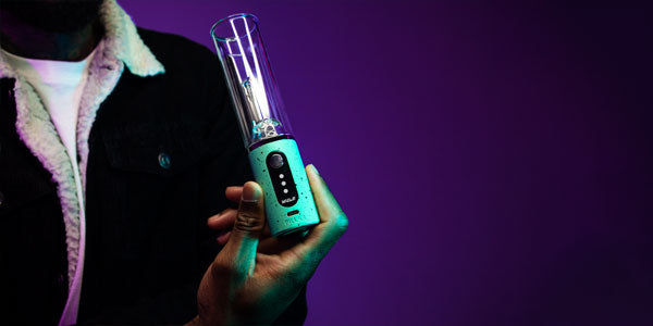 man holding the Wulf Pillar Concentrate Vaporizer inside studio with purple background