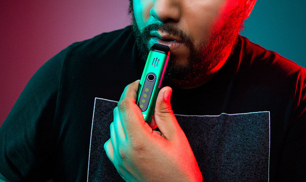 Person holding a teal WULF Florat vaporizer under red lighting