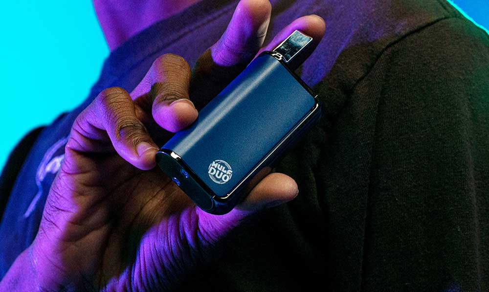 Person holding a blue WULF Duo 510 thread battery under purple lighting