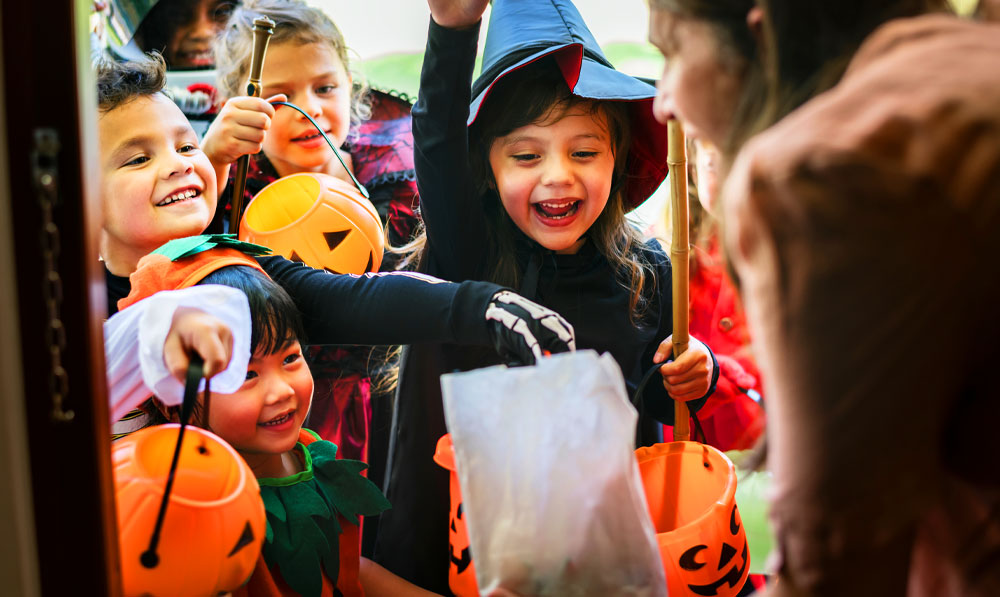 Woman opening up the door to kids in costumes trick or treating