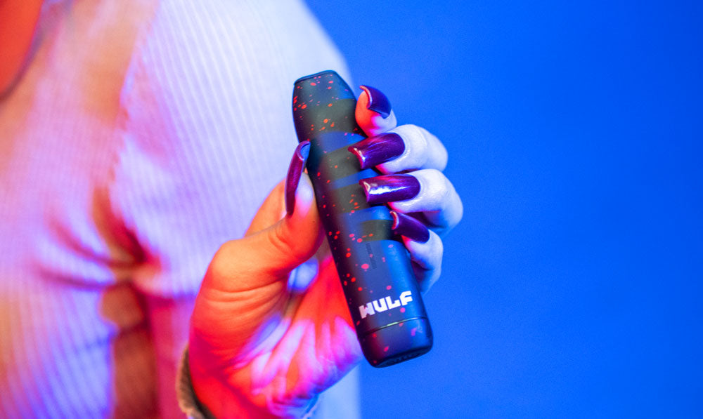 Woman holding Wulf LX Slim in front of blue studio background under red lighting
