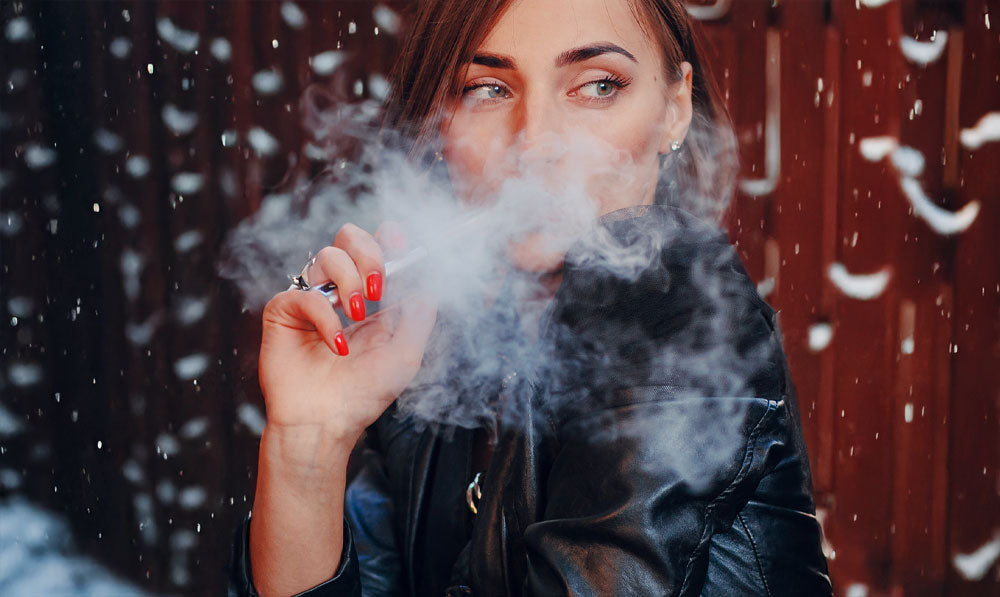 Woman vaping in the cold with snow falling