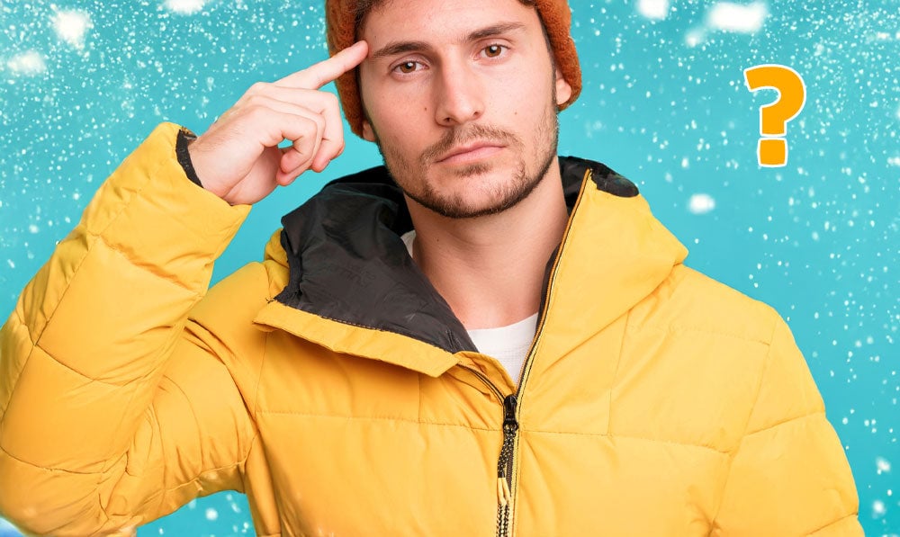 Man in heavy snow jacket standing confused with snow falling behind
