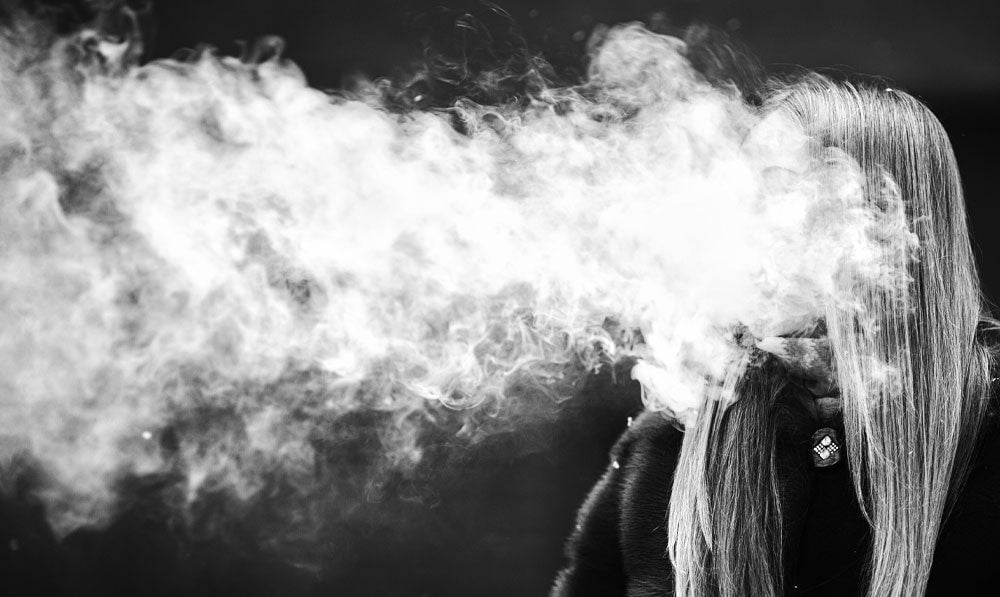 Woman vaping big cloud outside