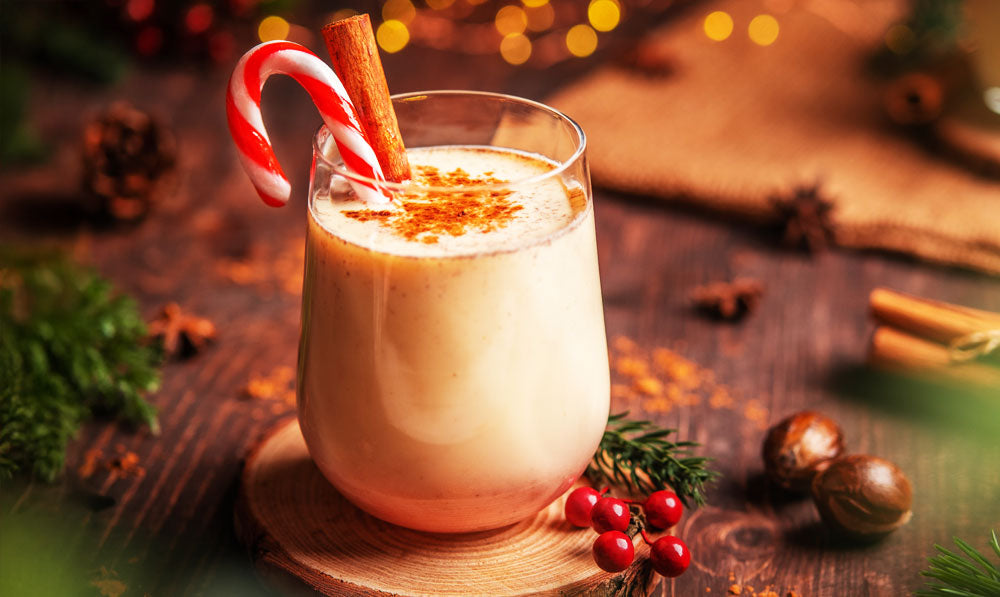 Egg Nog with cinnamon on wooden surface with festive decorations