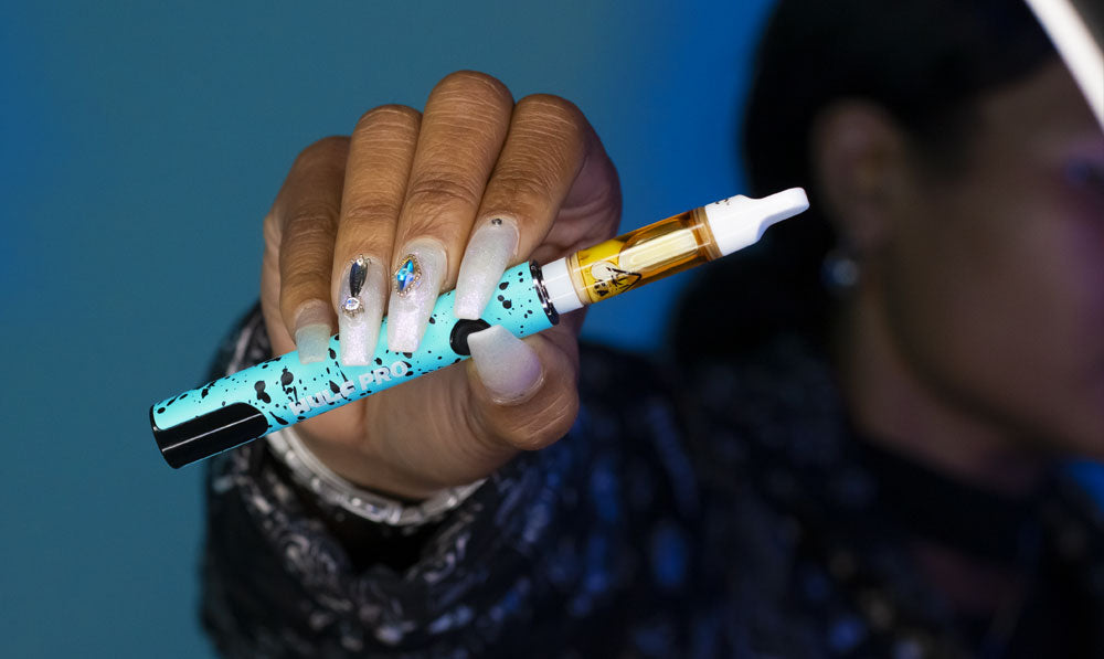 Woman holding teal Wulf Pro unit in front of blue studio background