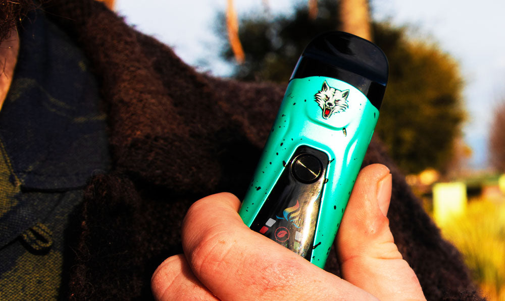 Person in a cosy jacket holding a teal WULF Flex dual use vaporizer