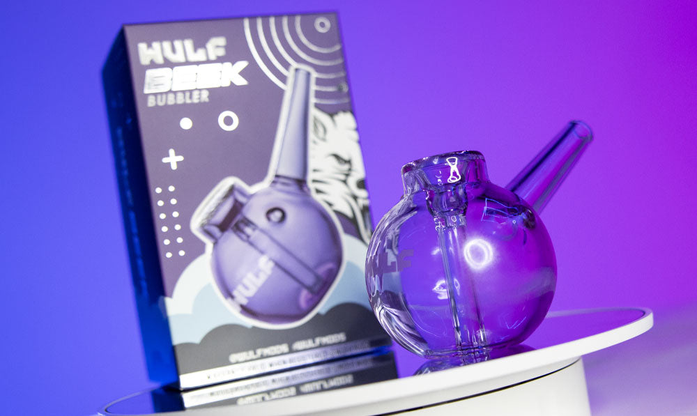 Wulf Mods Beek Bubbler on platform with packaging and purple lighting