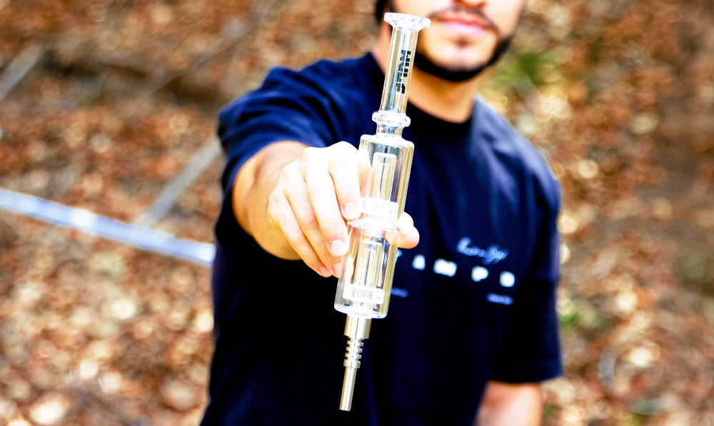 Man holding Clear Wulf Mods Nova Stack Nectar Collector in a forest clearing