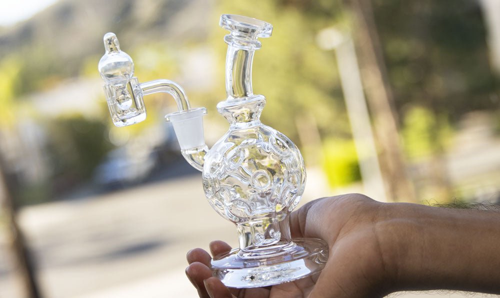 Person holding a WULF Atom recycler in front of a window