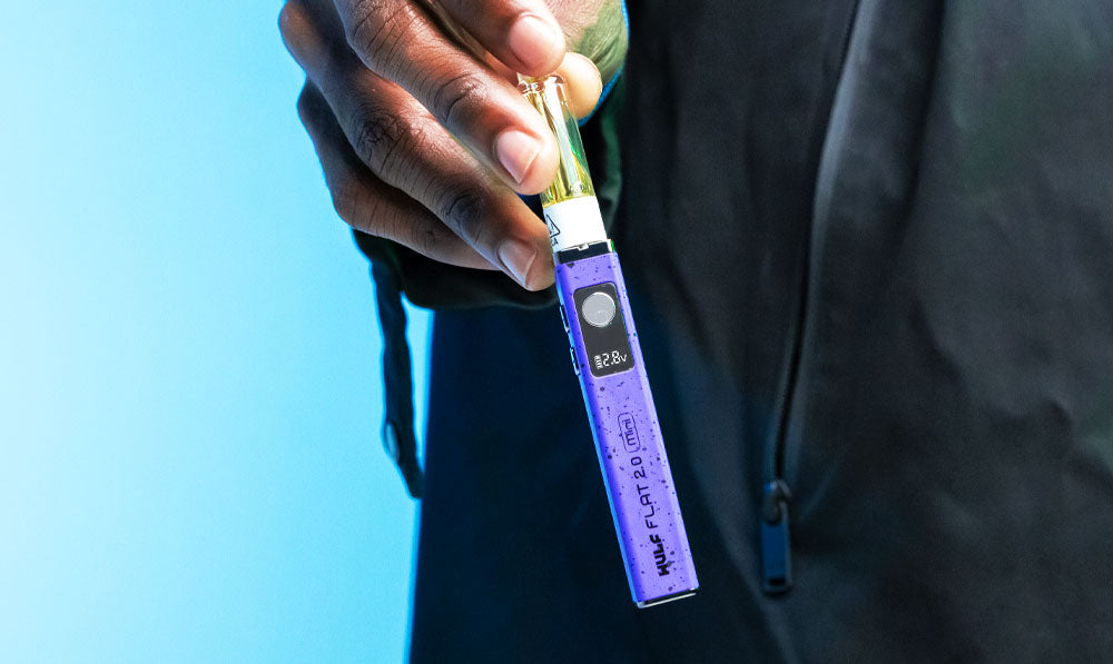 Man holding Wulf Flat Mini 2.0 in front of teal studio background