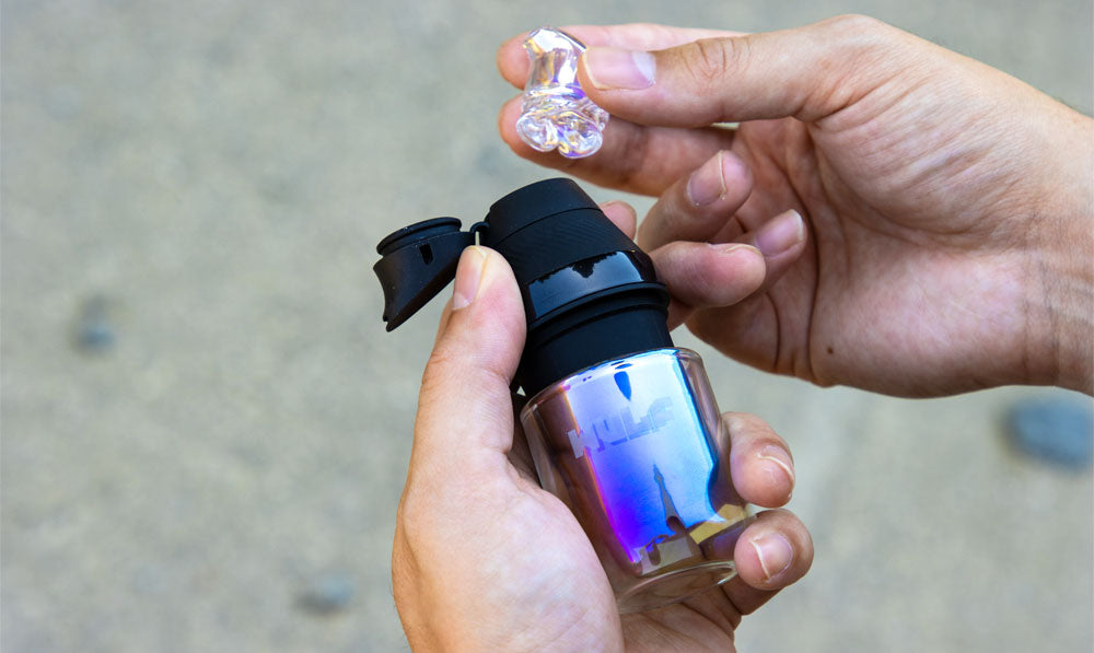 Hands holding a WULF Nest Puffco Proxy core attachment in an iridescent finish