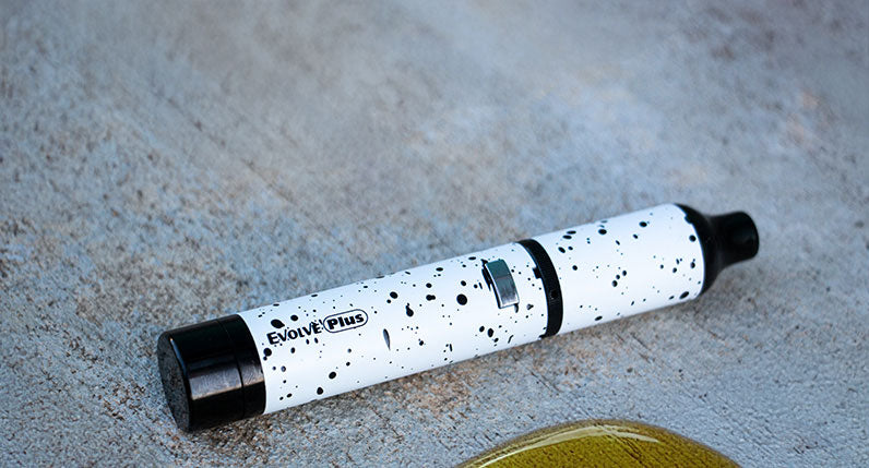 WULF Evolve Plus concentrate vaporizer in white with black spatter, lying on concrete