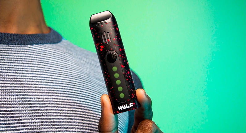 Person holding a WULF Flora portable dry herb vaporizer in black with red spatter