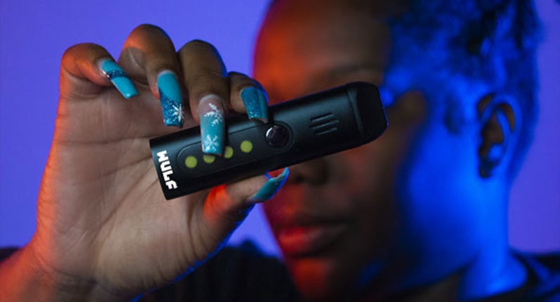Person with painted nails holding a WULF Flora portable dry herb vaporizer