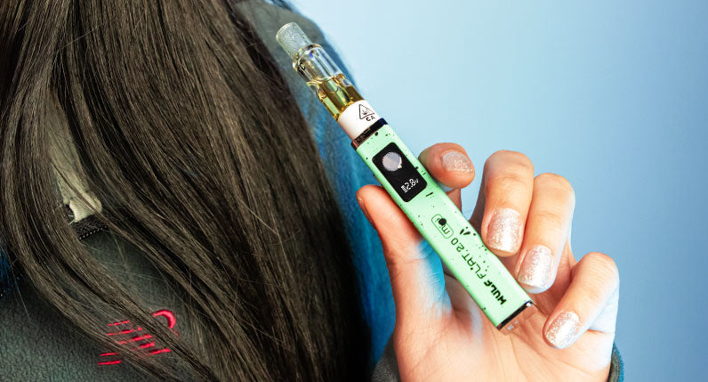 Woman holding Teal Black Spatter Wulf Mods Flat Mini 2.0 Variable Voltage Battery in front of blue background