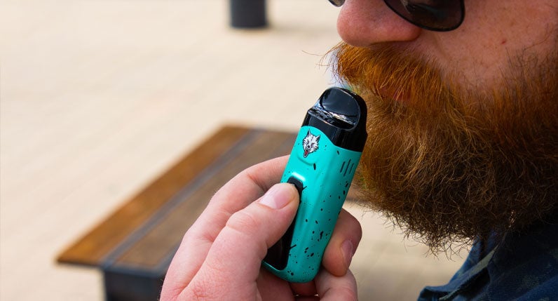 Person holding a teal WULF Flex dual use vaporizer
