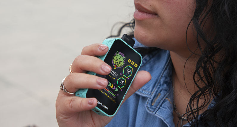 Person holding a WULF Recon Pro dual 510 thread battery with its colour screen lit